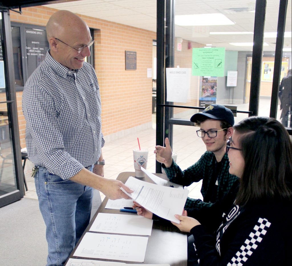 SSC Liberal Arts and Humanities Vice Chair John Bolander (left) hands off a ballot to a team of volunteers during the inaugural Trojan Speech and Debate Tournament last week.