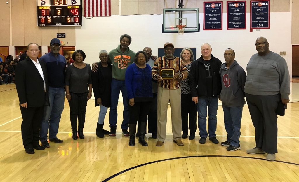 Group of people standing in a gym receiving an award.