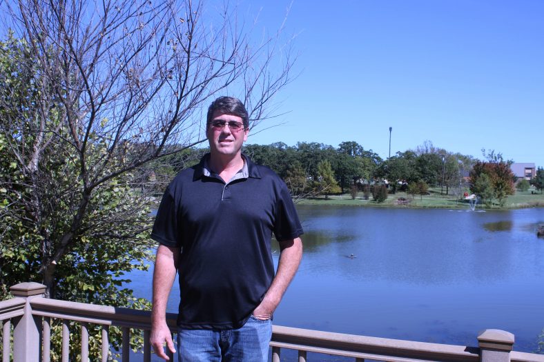 Director of Physical Plant and Campus Safety stands by campus pond.
