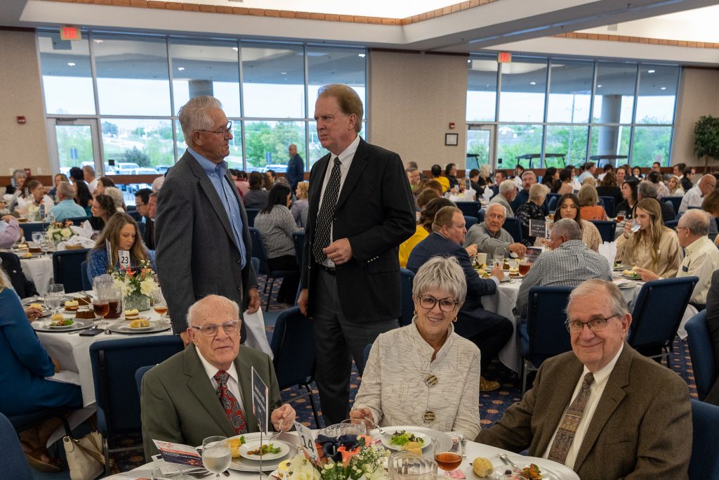 Standing in the background, former state senators Harry Coates (left) and Charlie Laster (right) chat before the Spring Banquet begins. In the foreground (pictured left to right), former SSC Regent Melvin Moran, current SSC Regent Marci Donaho and her husband Dale Donaho pose for a photo.