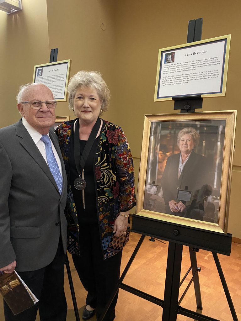 Melvin Moran (left) congratulates Lana Reynolds (right) as they stand next to her portrait. Portraits of each honoree were unveiled at the reception and will remain on display at the Oklahoma History Center until being moved to the Oklahoma State Capitol in Januar