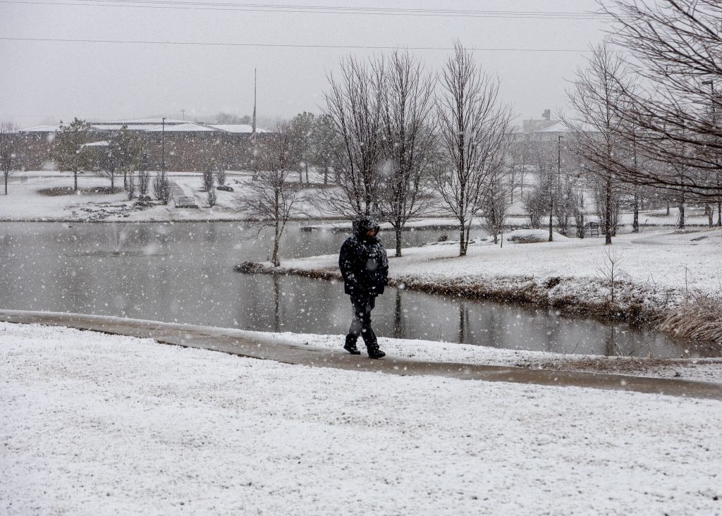 A student is pictured walking across campus in the snow.