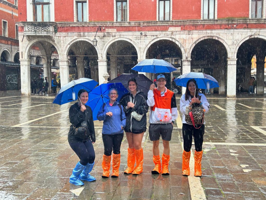 Trying to keep dry under umbrellas, SSC students pose for a photo outside of the Basilica di San Marco in Venice.