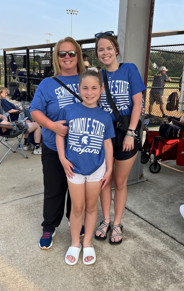 Pictured: Leslie Sewell (left) and her daughters, Blakely (right) and Briar (center) cheer on the Trojans softball team during their appearance at the NJCAA National Softball Championship Tournament in Oxford, Alabama on May 23, 2003.