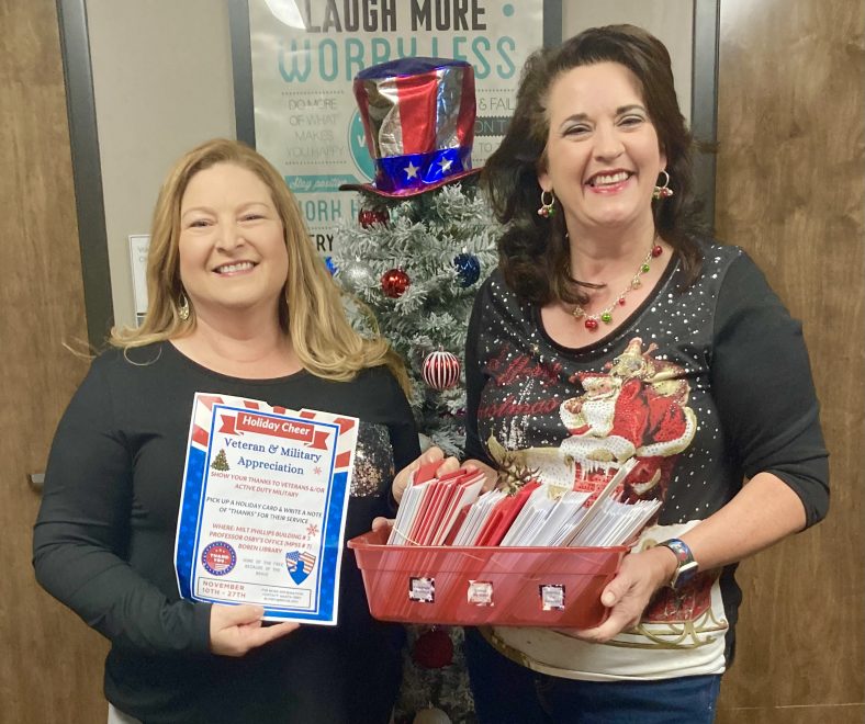 Melissa Overfield (left), the Center for Development & Civic Engagement at the Oklahoma City VA Medical Center, accepts holiday greeting cards signed by the SSC campus community by Professor of History Mart Osby (right).