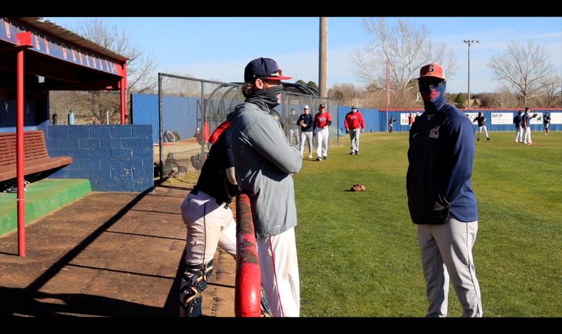 Seminole State College BAseball players stand outside the dugout during pre season scrimmage