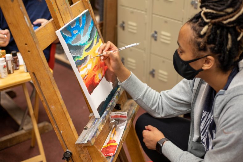 Seminole state student paints on canvas during art appreciation class.