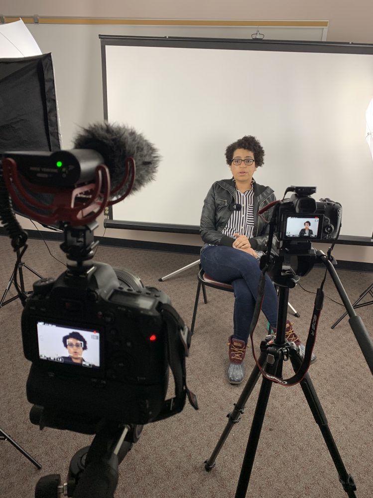 SSC Assistant Professor of the Arts Program, Lynette Atchley, sits in front of a white backdrop with two cameras focused on her during an interview shot for one of the schools digital media projects.