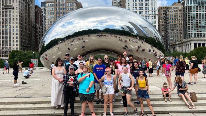 Group of students stand in front of statue