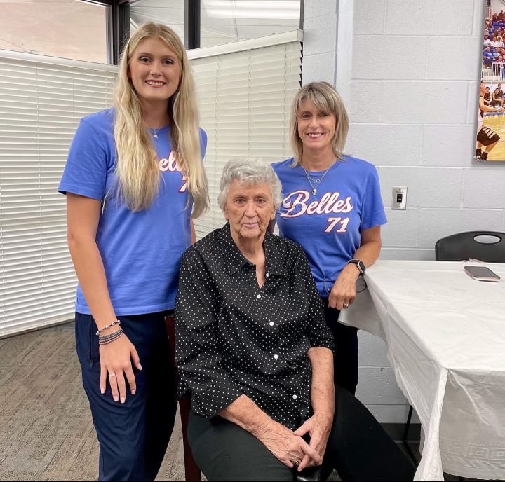 Dixie Woodall seated poses with current SSC coaches Rita Story-Schell and Jentry Holt