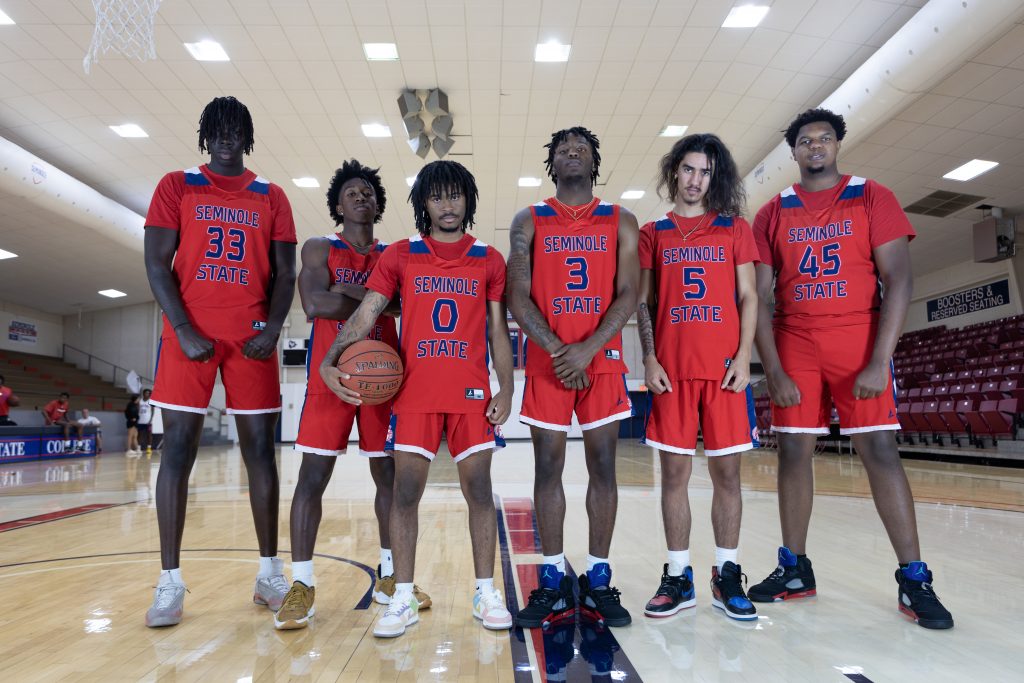 men's basketball team pose in gym