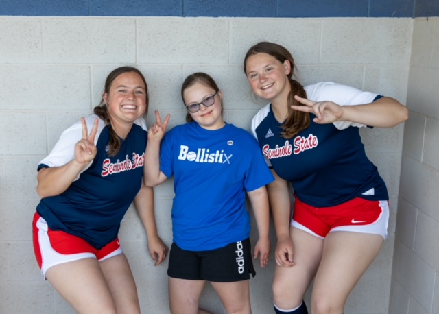 Pictured are SSC softball players Elizabeth Taber of Oklahoma City (left) and Kenzie Kauk of Clinton (right) pose for a photo with Addison Pearce of Shawnee (center) while she waits to bat.