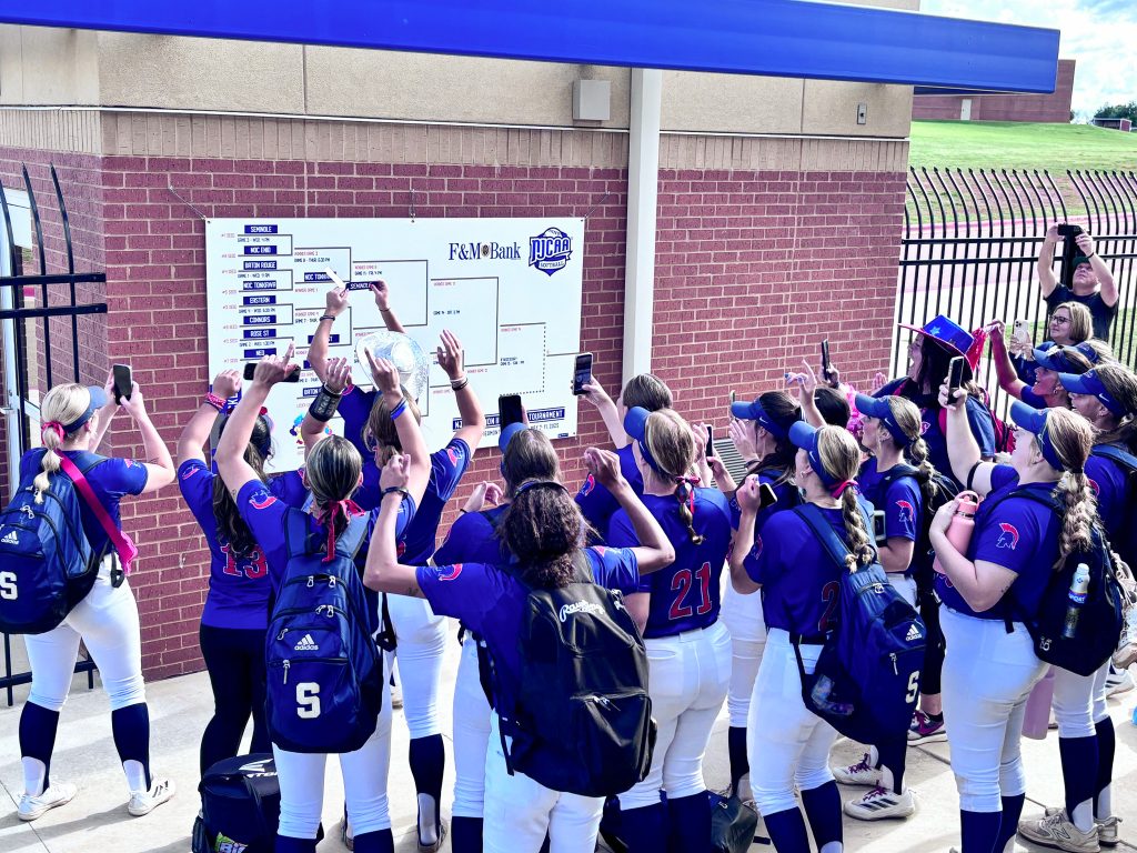 In this photo, SSC Softball team members gather around a tournament bracket.