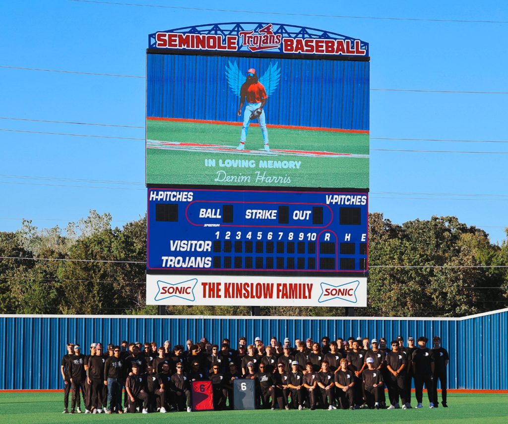 Group photo of the SSC Trojan baseball team holding Harris's framed jerseys.