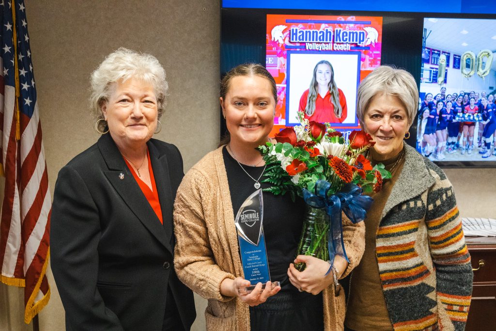 In this photo, SSC President Lana Reynolds (left) and SSC Board of Regents Chair Marci Donaho (right) present Women’s Volleyball Head Coach Hannah Kemp (center) with a plaque and flowers to commemorate her 100th career win at Seminole State College during the Oct. 30 Board of Regents meeting.