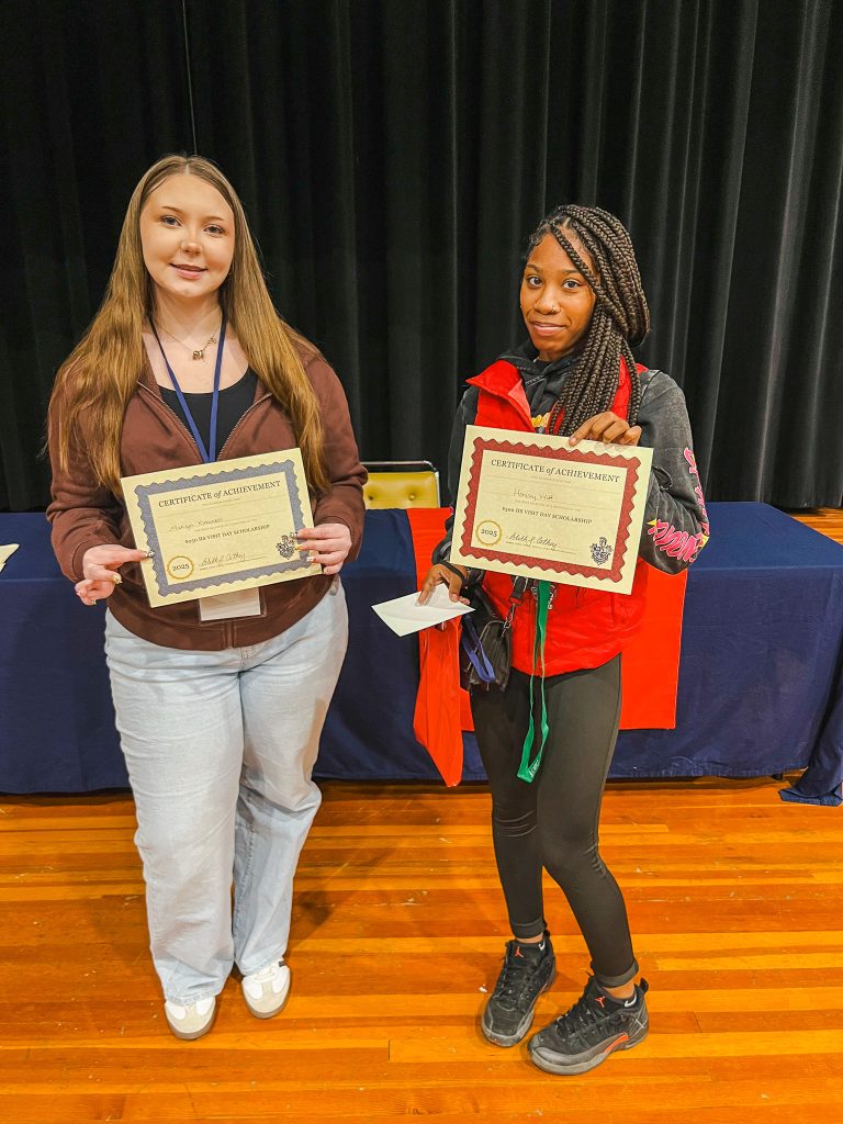 Two students pose with scholarship certificates.