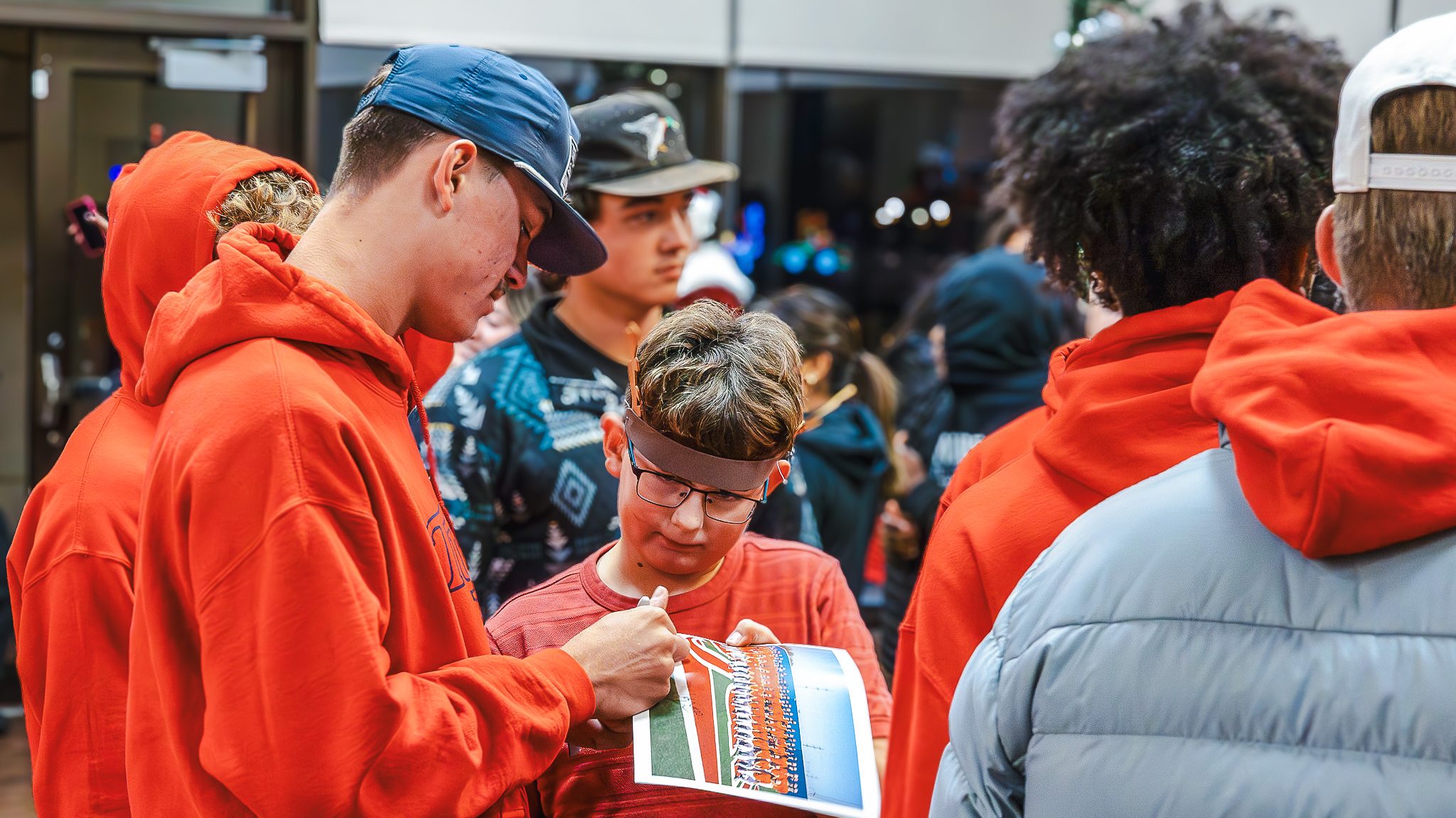 In this Photo, Trojan baseball players autograph a team photo for Prague fifth grader Braylen Dale.