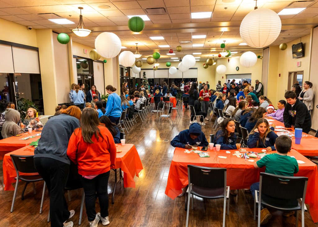 In this photo, SSC athletes, coaches, faculty and staff are pictured with families from the community as they work on holiday arts and crafts projects. 