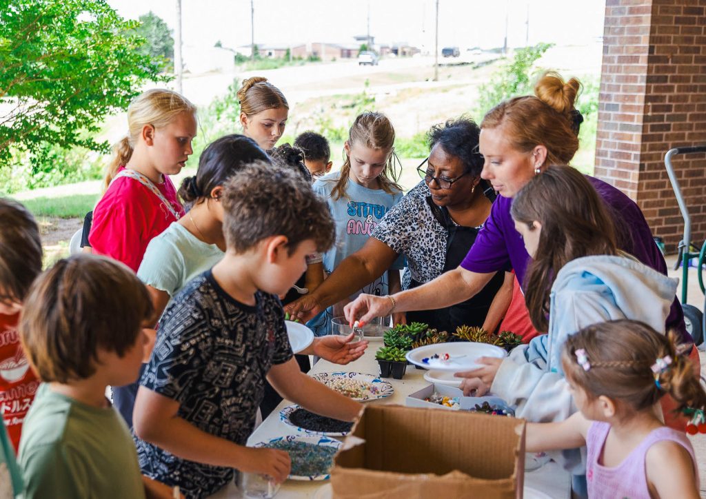 In this photo, SSC faculty and staff members are shown helping children plant succulents during the 2025 Kids on Campus Sumer Camp.