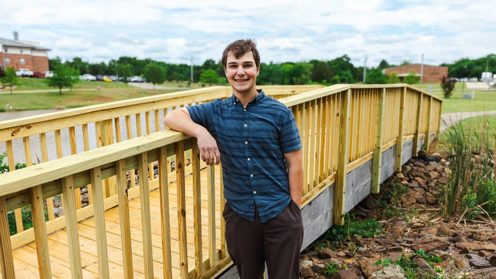 In this photo, Caleb Philips, a senior at The Academy of Seminole, stands beside the newly reconstructed bridge alongside the north pond on Seminole State College’s campus.
