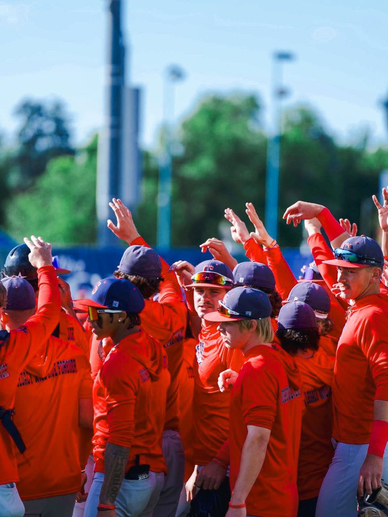 In this photo, the Trojan baseball team is shown huddled together before the start of a game.