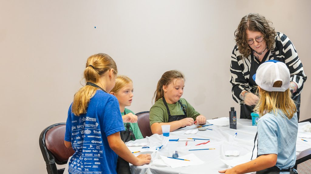 In this photo, Seminole Citizen of the Year Jacqi Dill helps Kids on Campus attendees with preparing paint for the daily art project.