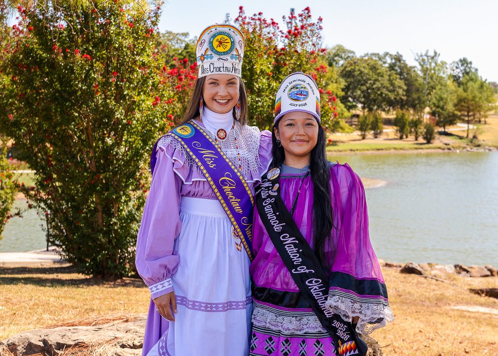 In this photo, Miss Choctaw Nation Mia Reich (left) and Miss Seminole Nation Alivia Wapskineh stand in front of the south pond on Seminole State College’s campus.
