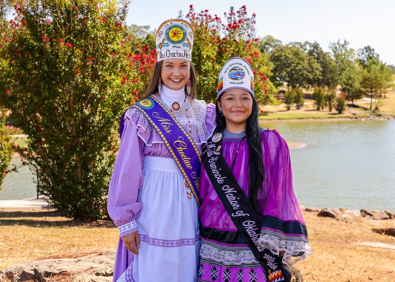 In this photo, Miss Choctaw Nation Mia Reich (left) and Miss Seminole Nation Alivia Wapskineh stand in front of the south pond on Seminole State College’s campus.