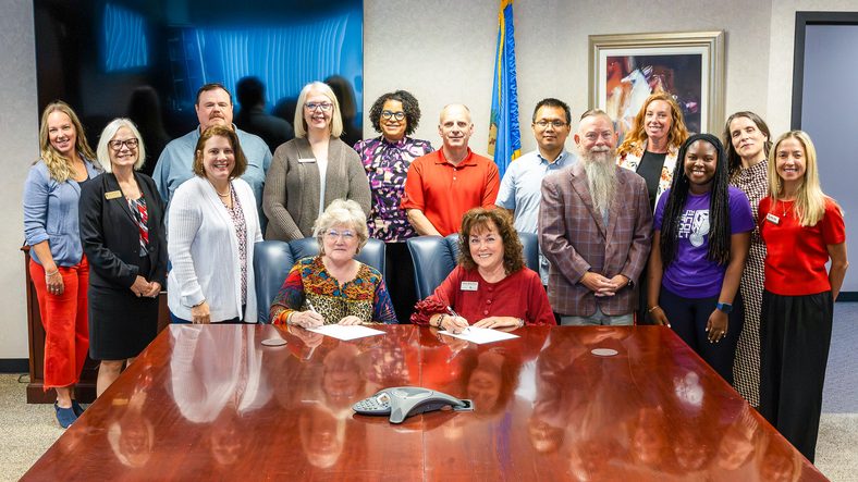 In this photo, Seminole State College and the University of Oklahoma Polytechnic Institute representatives pose for a group photo. Seated, from left, are SSC President Lana Reynolds and Dr. Teri Reed, Director of the OU Polytechnic Institute. Standing, from left, are SSC Health Sciences Division Chair Emily Carpenter; Dr. Randa Shehab, OU Senior Associate Dean of Engineering; SSC IT Director/CISO Marc Hunter; SSC Dean of Instruction Jessica Isaacs; SSC Vice President for Finance, Grants and Enrollment Melanie Rinehart; SSC Faculty Senate President Lynette Atchley; Dr. John Hassell, OU Associate Professor; Dr. Chenggang Wang, OU Assistant Professor; SSC Vice President for Academic and Student Affairs Dr. Bill Knowles; SSC STEM Division Chair Wendy Slusher-Rich; SSC Assistant Professor of Computer Science Alicia Bailey; Dr. Johnnie-Margaret McConnell, OU Director of Transfer Student Success; and Danielle Dunn, OU Associate Vice President of Marketing.